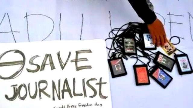 Sebuah tulisan dan ID Card Jurnalis diletakan di atas sebuah spanduk, tanda protes terhadap kriminalisasi jurnalis. (Ist/Int)