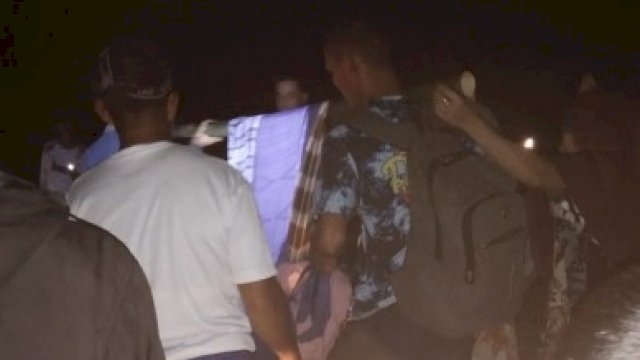 Terlihat sekumpulan warga tengah membawa seorang ibu-ibu yang akan melahirkan dengan cara ditandu dan dibawa secara berganti-gantian demi sampai ke Puskesmas, Sabtu (20/11) malam. [Istimewa]