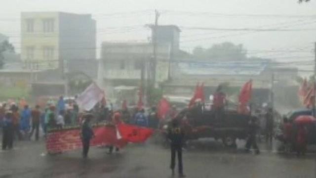 Hujan-hujanan, puluhan buruh turun ke jalan melakukan aksi demonstrasi di Jalan Urip Sumoharjo, Makassar, Kamis (23/12). TROTOAR/MAULANA