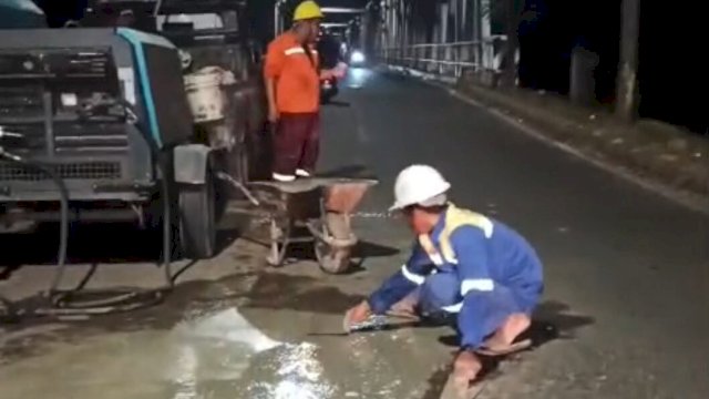Pekerja Sedang melakukan Penambalan Jalan berlubang di jalan Metro Tanjung unga Kota MAkassar